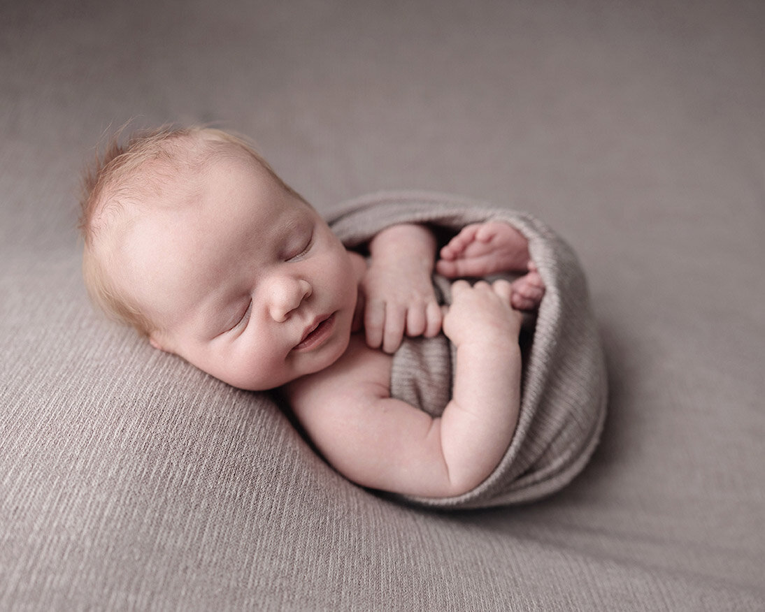 Baby boy sleeping in a curling round position in Pittsburgh photography studio