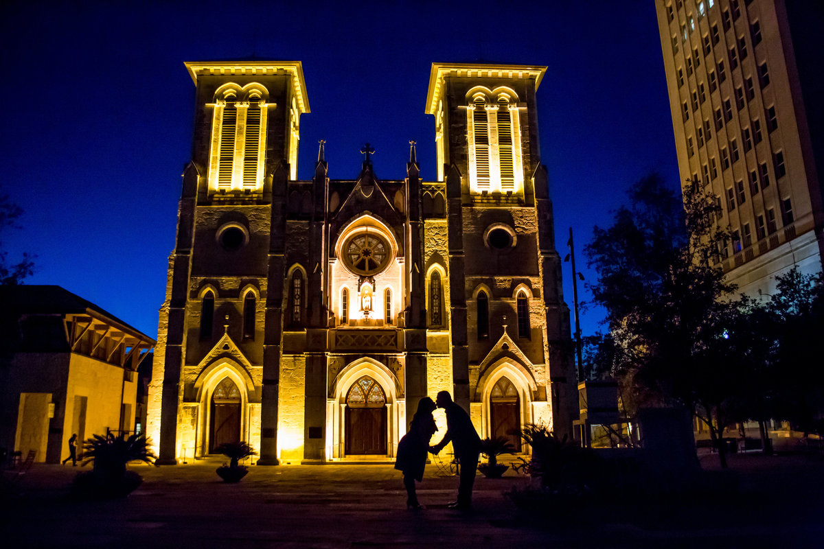 Silhouette of engaged couple kissing in front the San Fernando Cathedral in San Antonio in the Main Plaza at night.