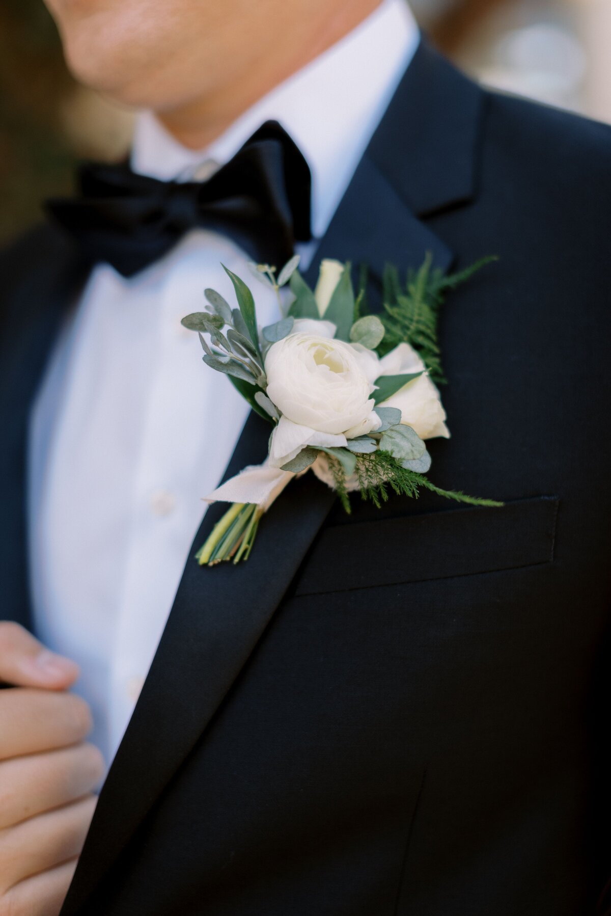A boutonniere of a white rose and renuncula for the groom.