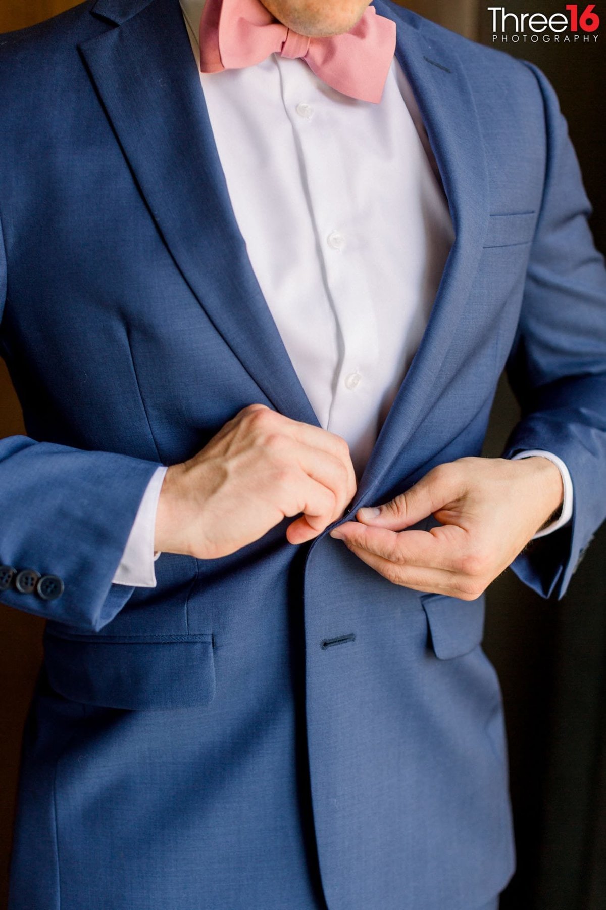 Groom buttoning his coat before the wedding