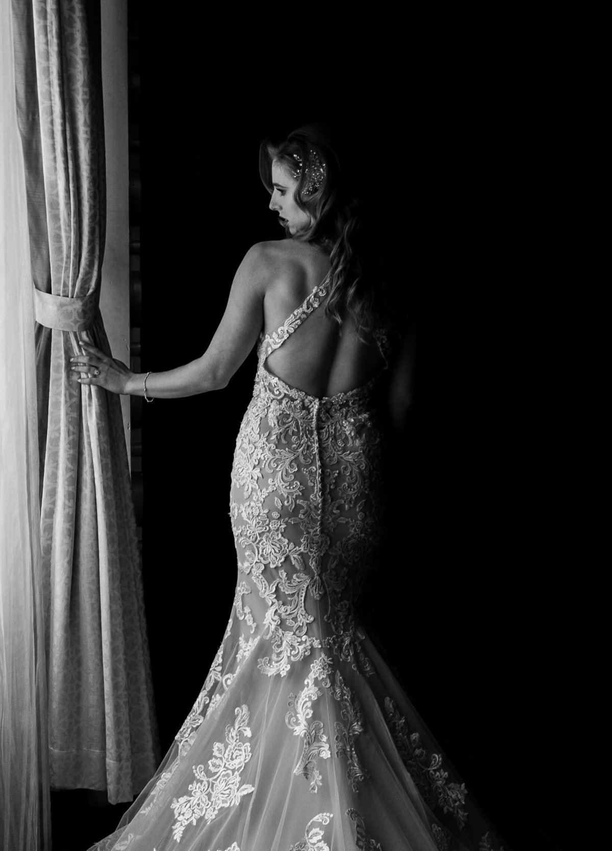 A bride featuring her wedding dress by a window.