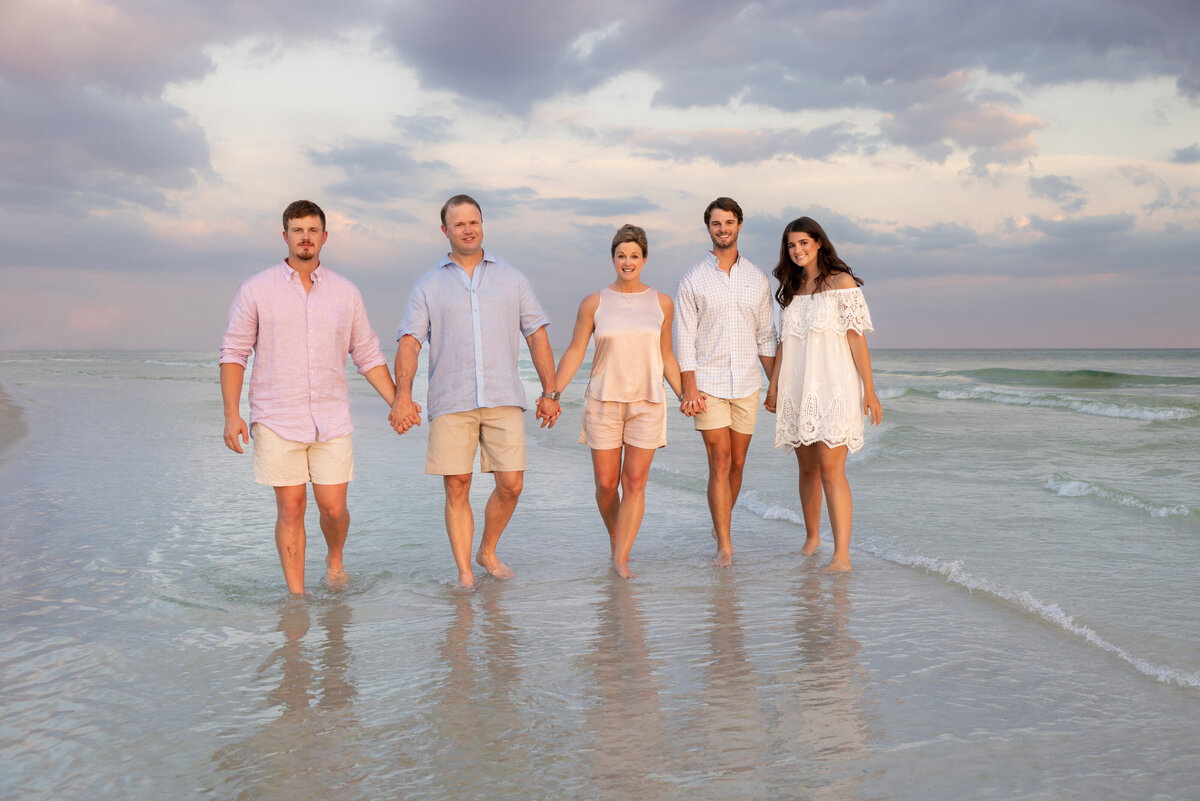 A family holding hands and walking in shallow water