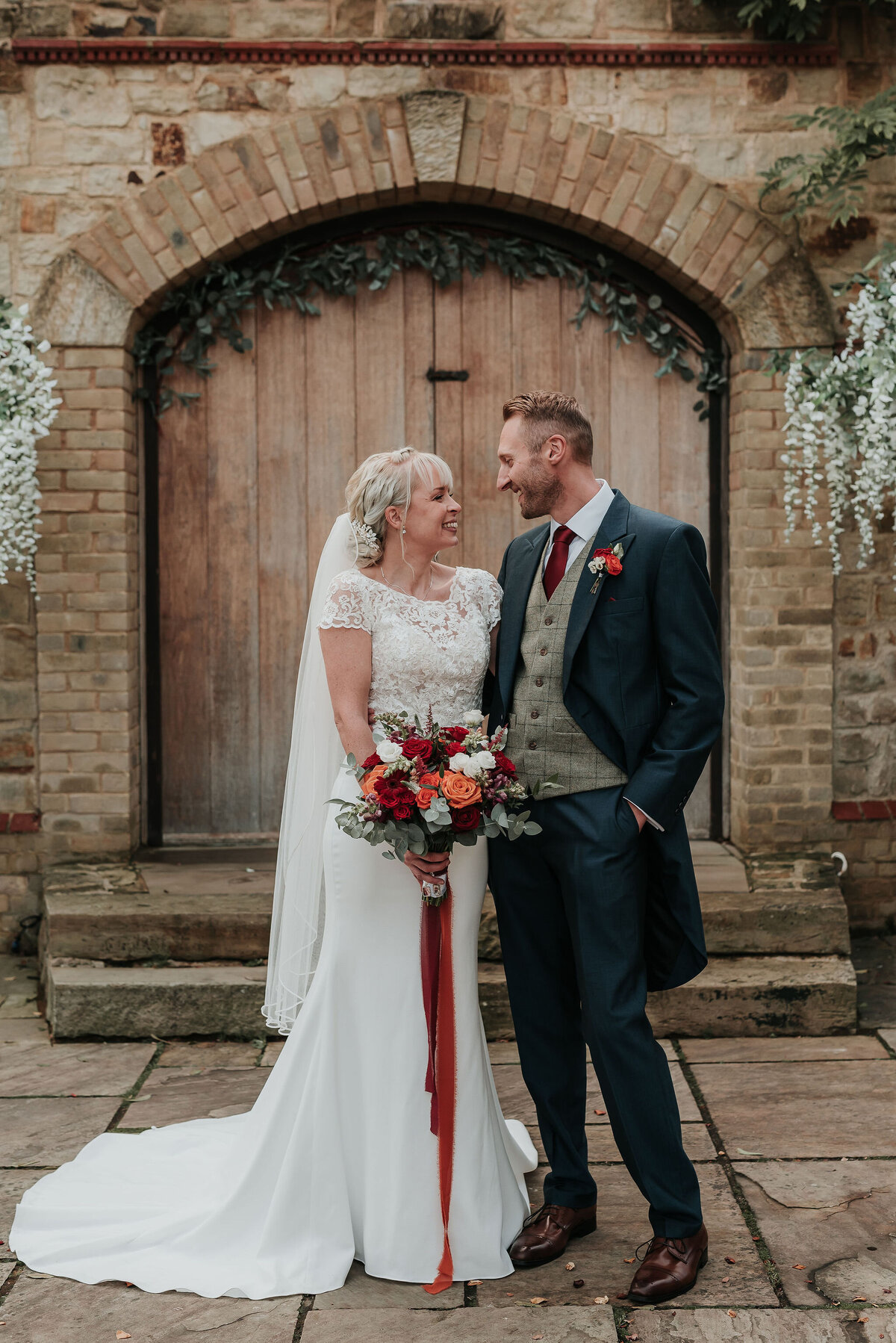 Bride holding Autumnal wedding bouquet with her husband at their joyful autumn wedding at The Ravenswood
