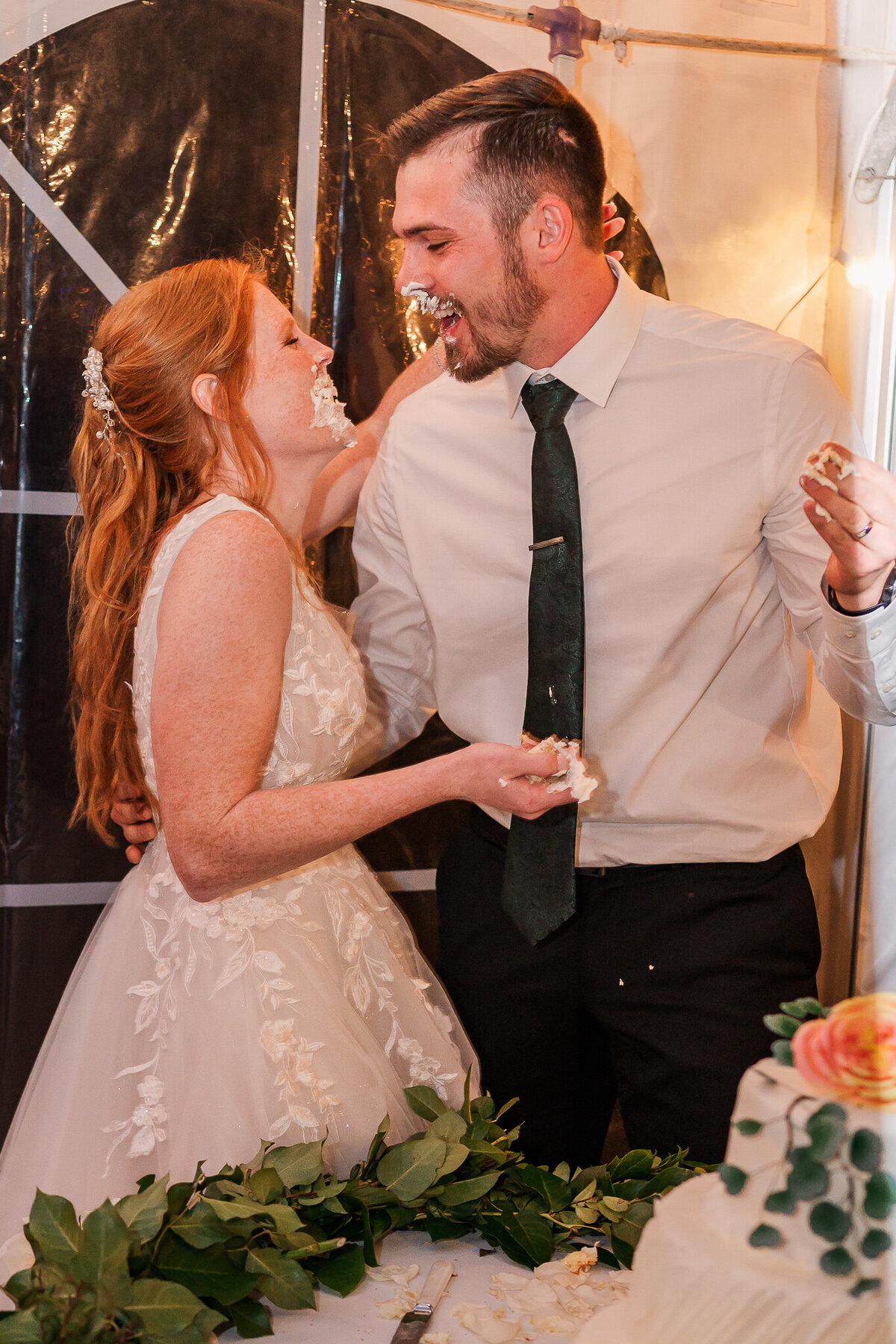 A happy bride and groom feeding each other wedding cake during their wedding reception by JoLynn Photography, a Raleigh wedding photographer