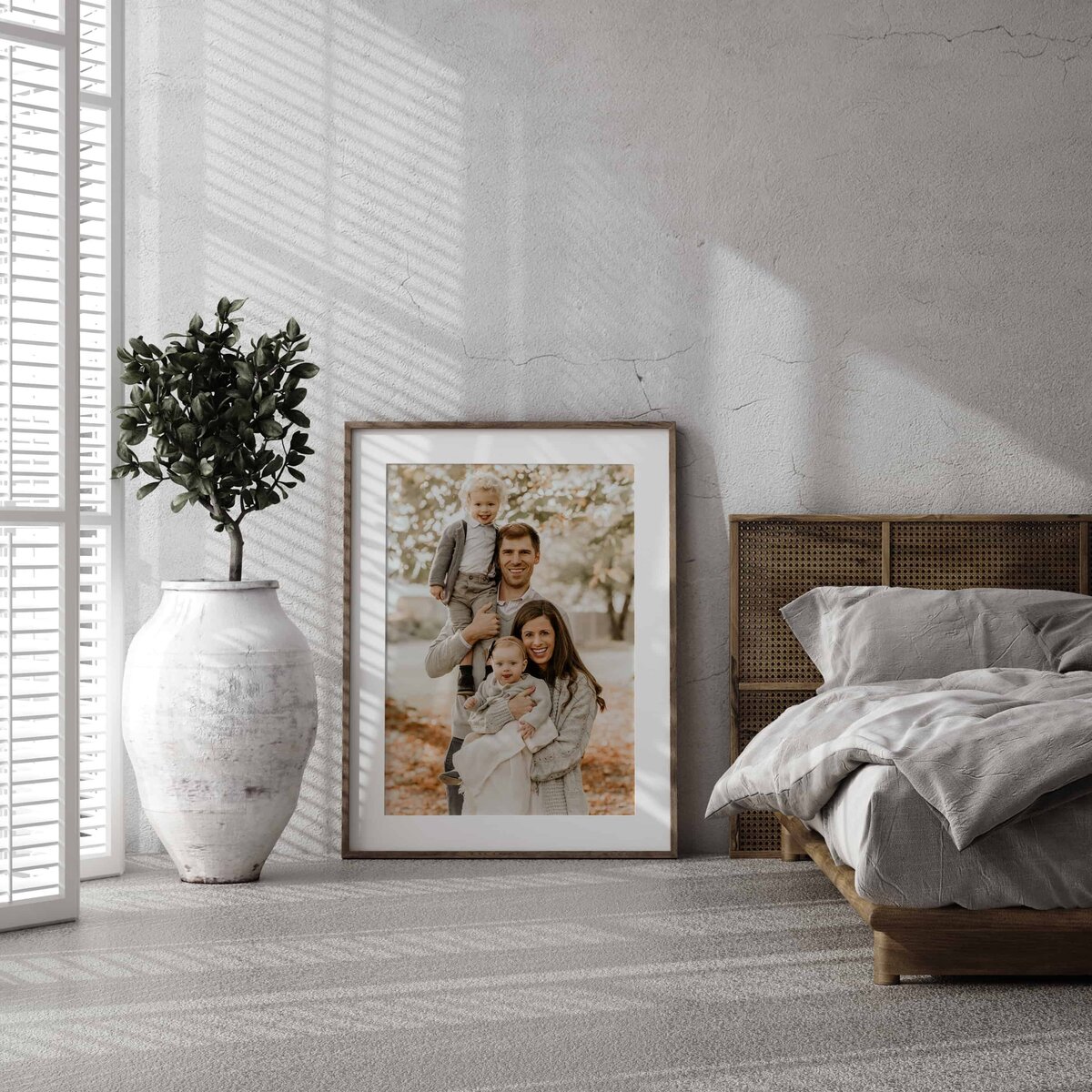 Et stort rammet bilde fra familiefotografering i Oslo står på gulvet i et soverom.