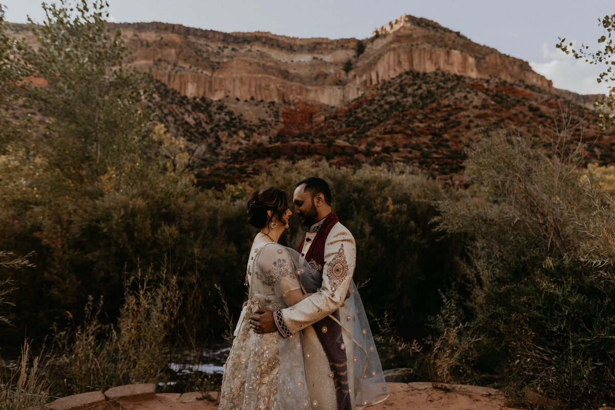 bride and groom hugging each other in front of the red rocks in Jemez Springs, NM