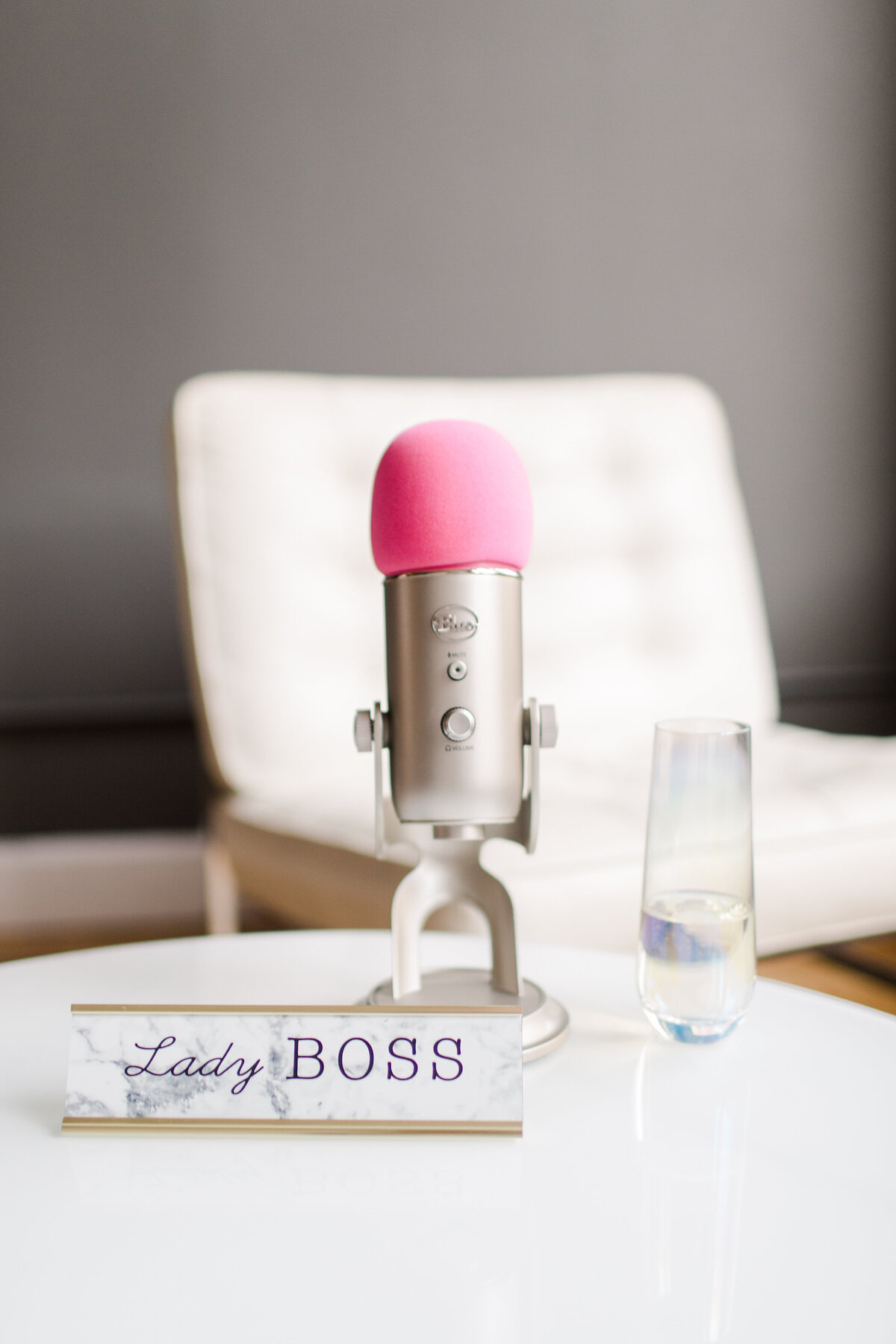 pink micraphone on a white desk with a white chair behind it and a lady boss sign in front