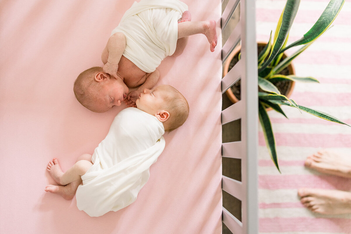 Newborn twin girls sleep in crib