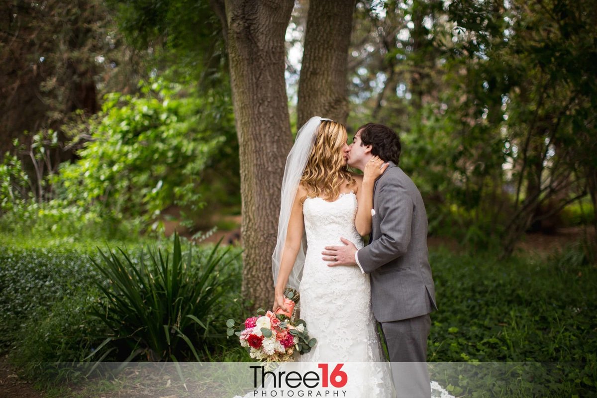 Bride and Groom share a passionate kiss in the middle of the Fullerton Arboretum