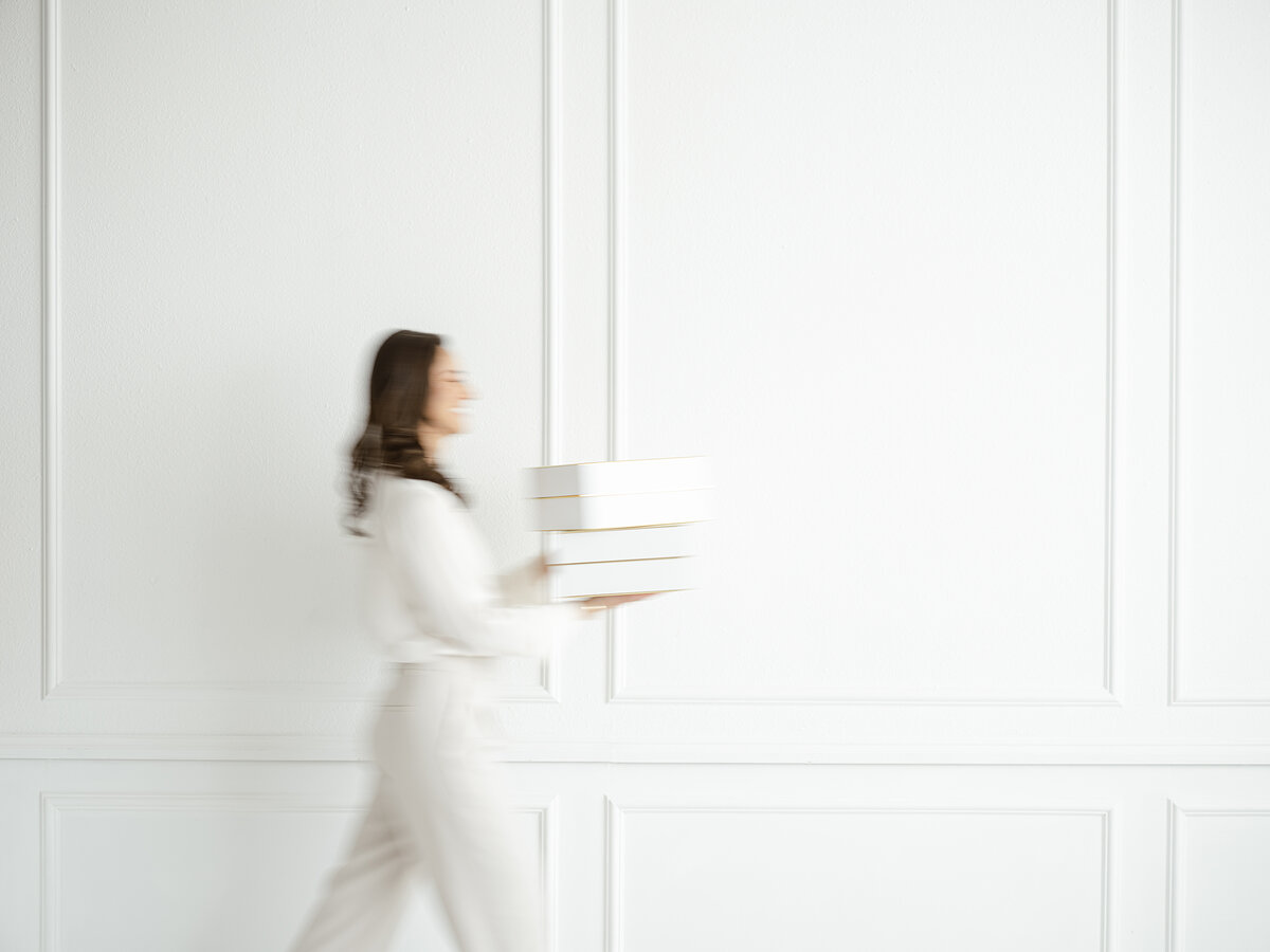 Headshot photo of a DFW business owner carrying books and walking across the room.