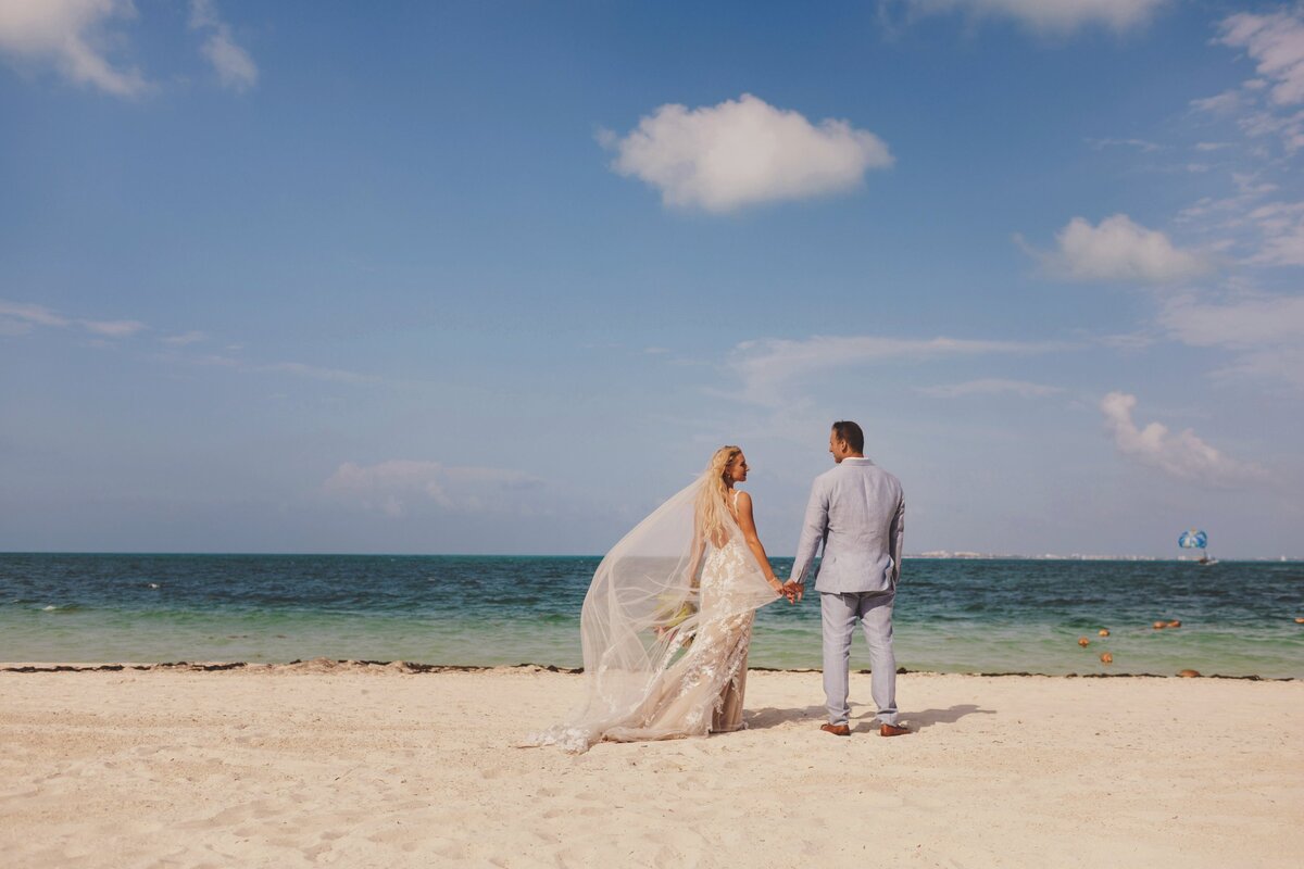 Bride and groom holding hands enjoying the view after wedding in Cancun