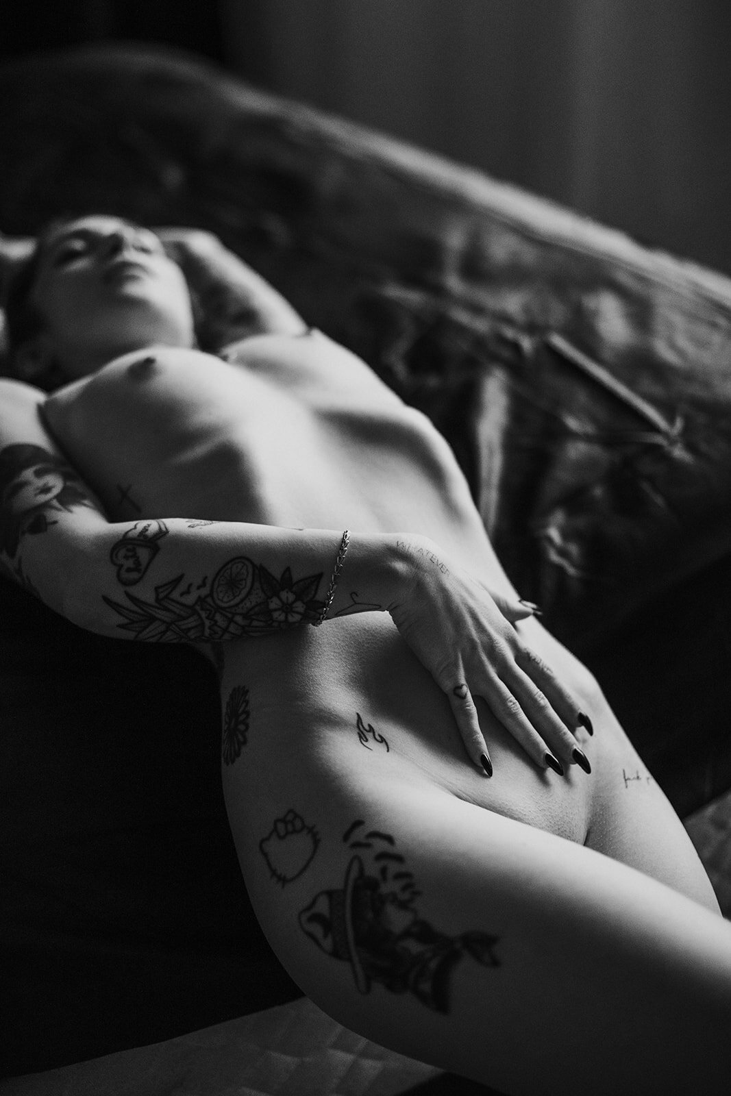 tattooed model poses on bed in boudoir studio vancouver
