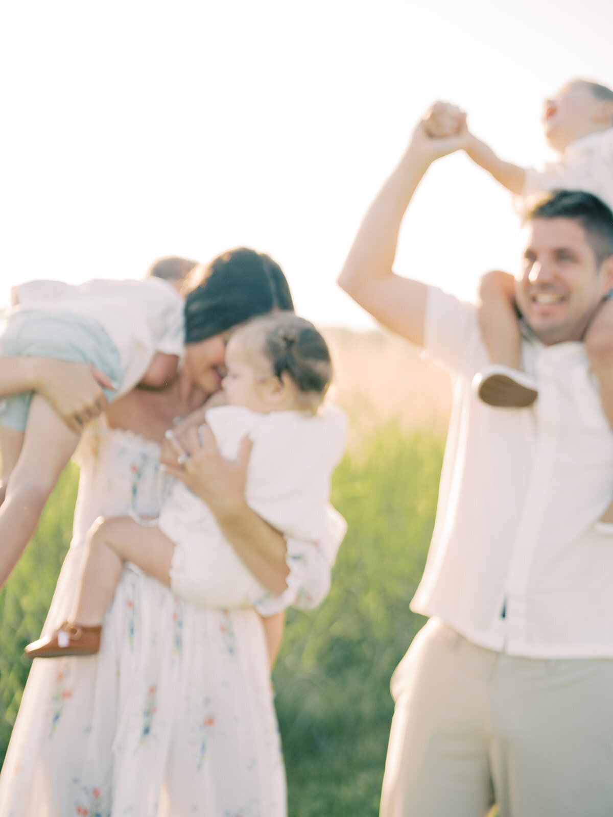 Out-of-focus image of a family of five playing in a grassy field.