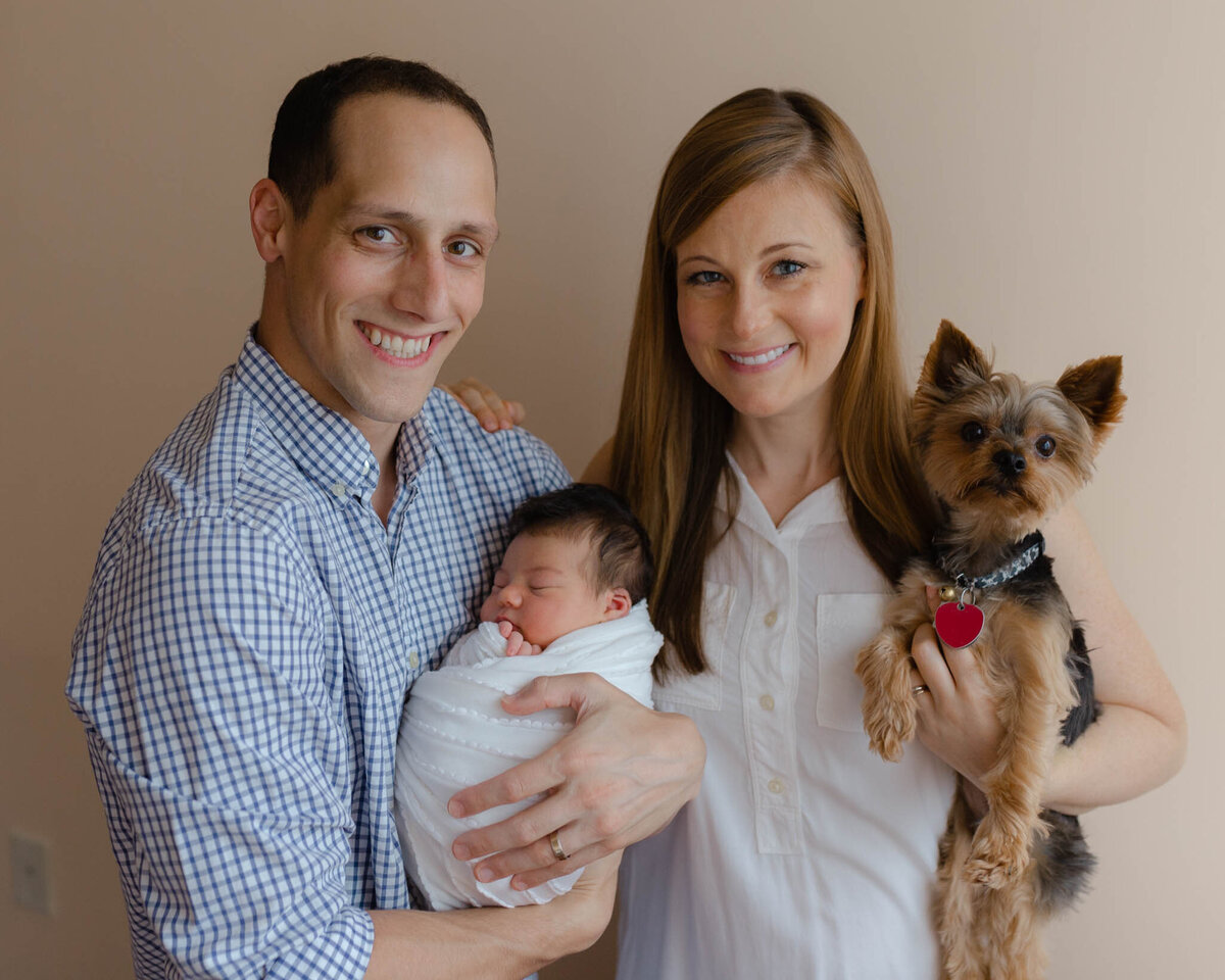 family with dog holding newborn baby