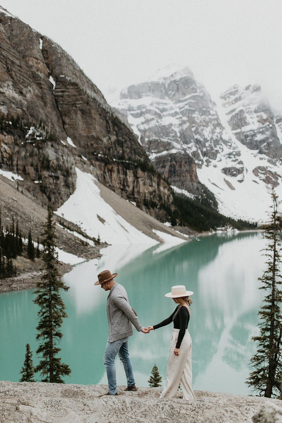 Couple walking hand in hand at Lake Louise, , captured by Nikki Collette, featured on the Brontë Bride Wedding Vendor Guide.