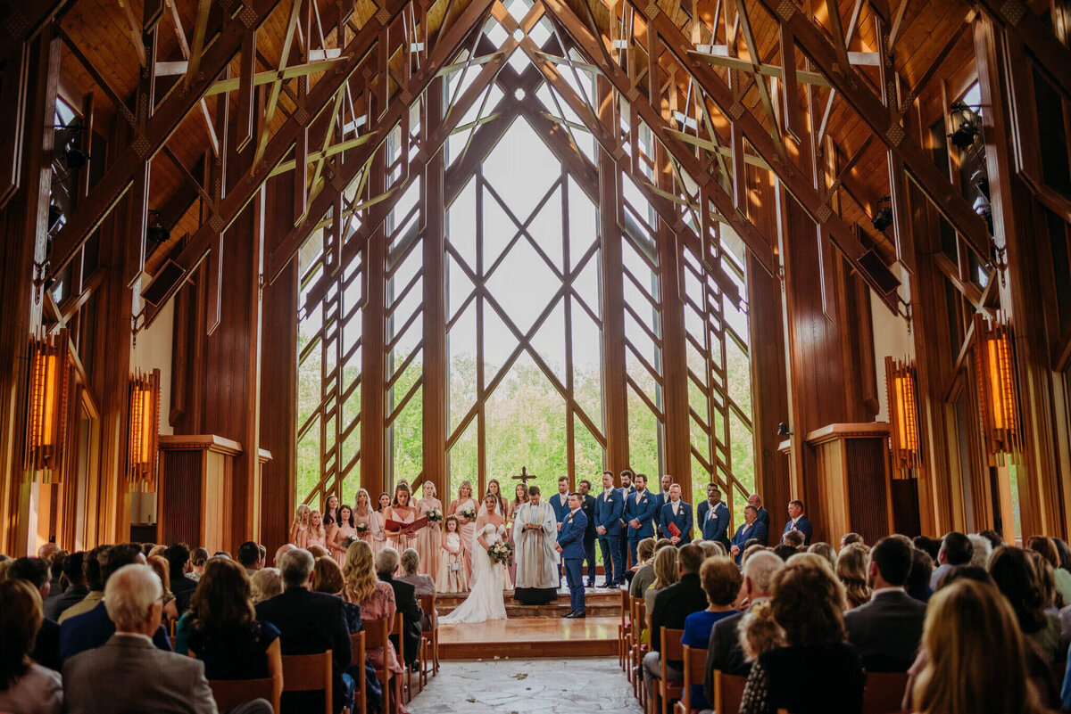 photo of a wedding ceremony in a glass chapel with wooden beams