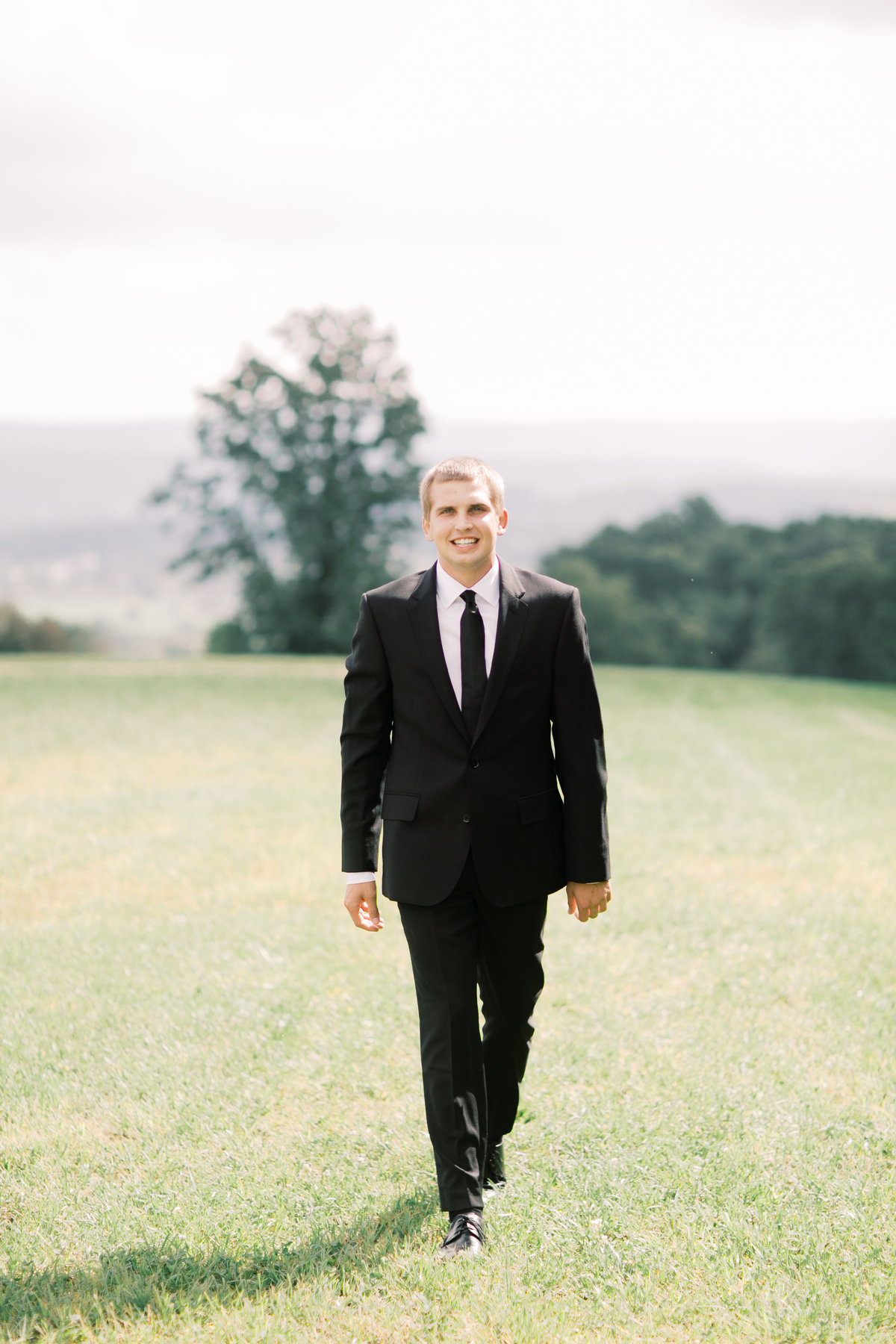 groom walking through grassy field