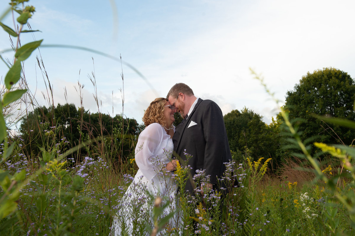 bride and groom in field of wildflowers