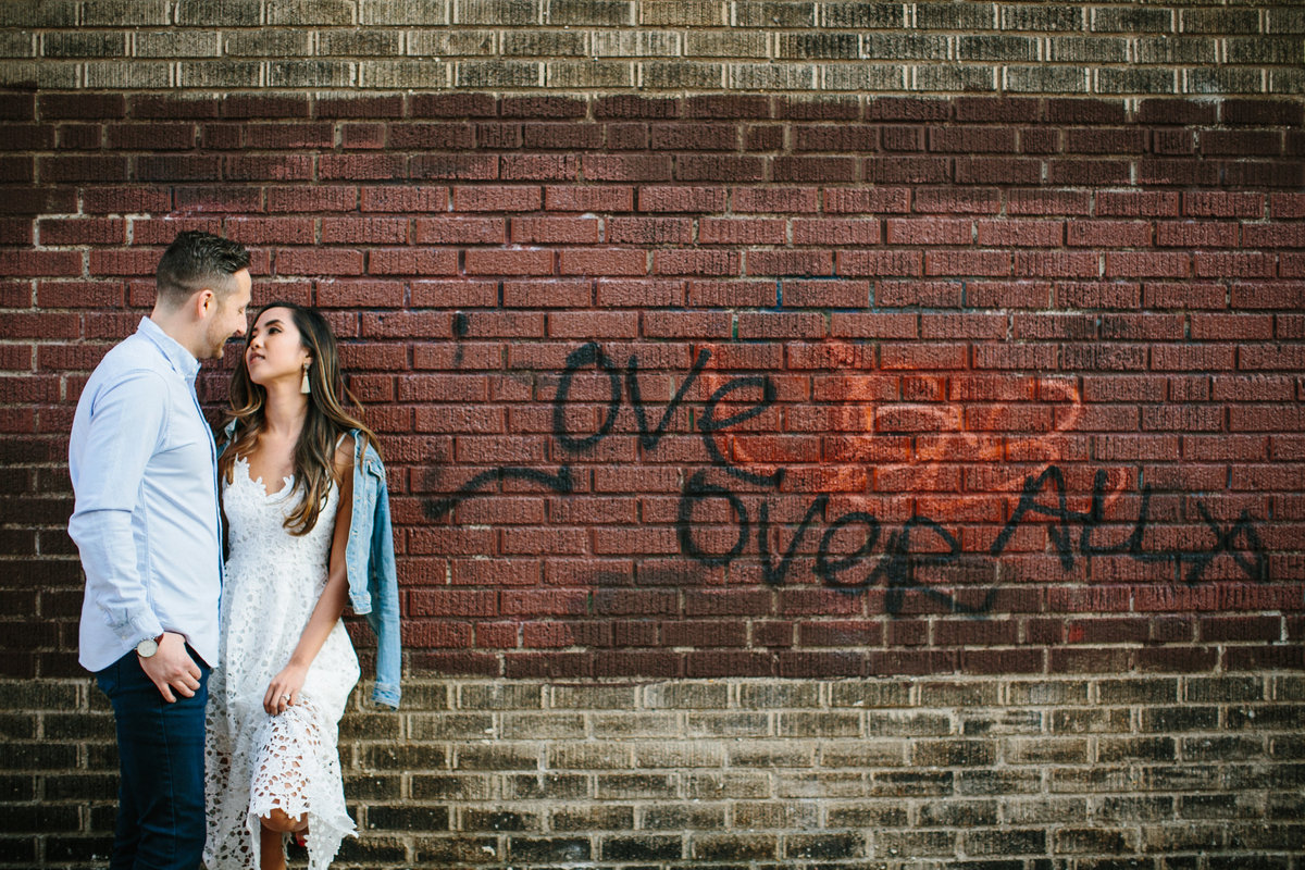 Engaged couple pose for a photo by love written graffiti in Old City, Philadelphia.