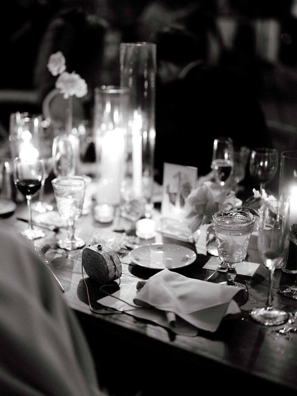 Black and white photo of a candle-lit wedding dining table with elegant cutleries at The Ausable Club, NY. Image by Jenny Fu Studio