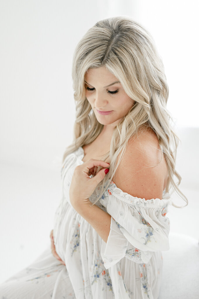 Blonde woman smiles and holds her pregnant abdomen By Nashville maternity photographer Kristie Lloyd