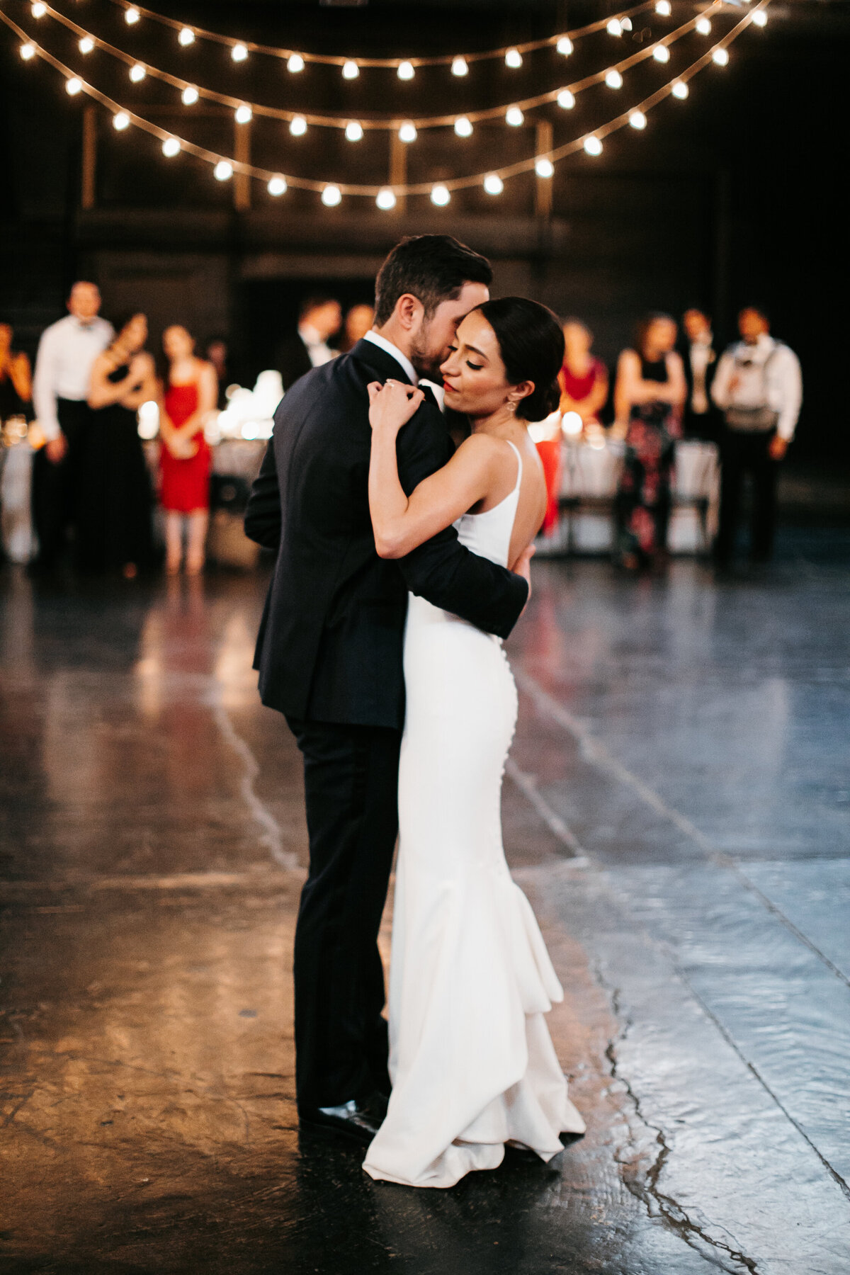 bride and groom first dance at reception under string lights