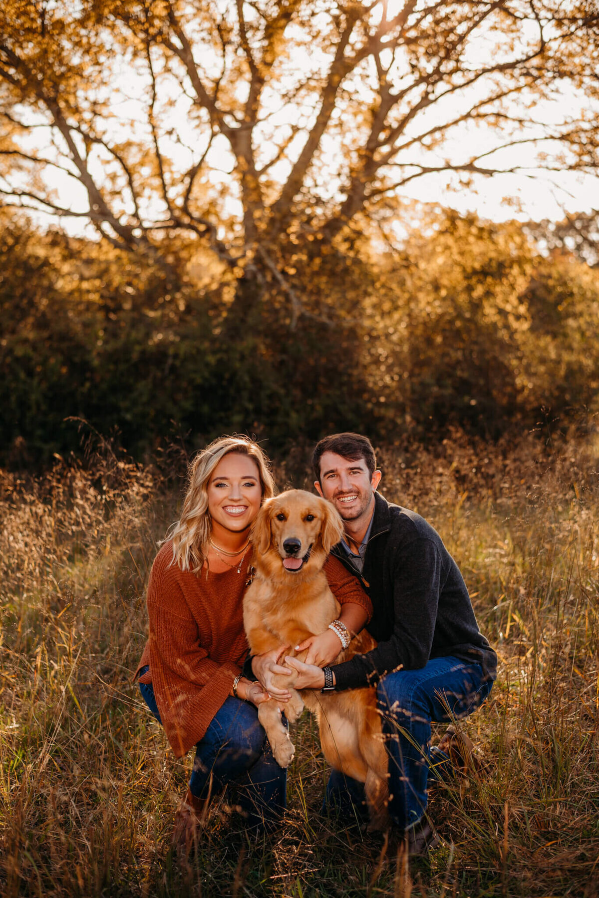 photo of a man and woman hugging their golden retriever