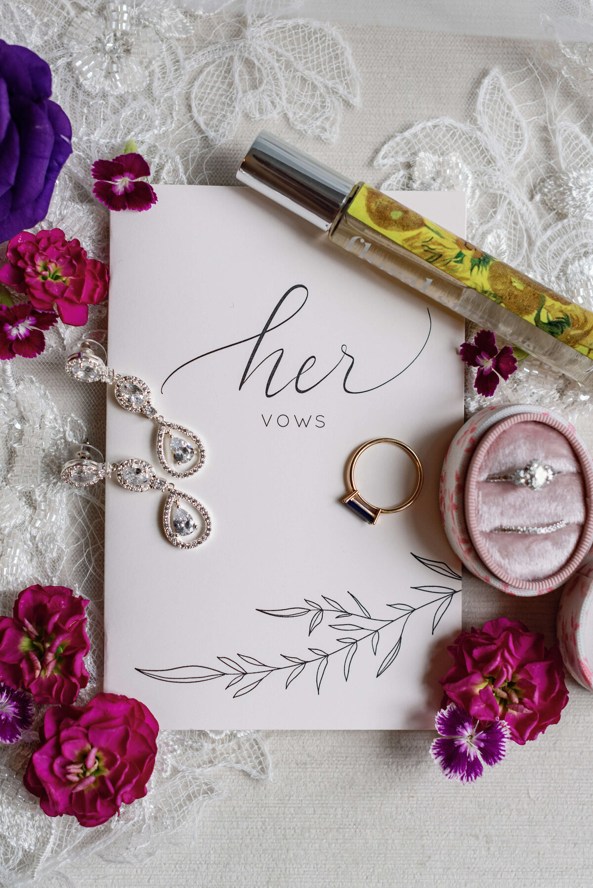 Wedding details including rings, vow book, earrings and perfume