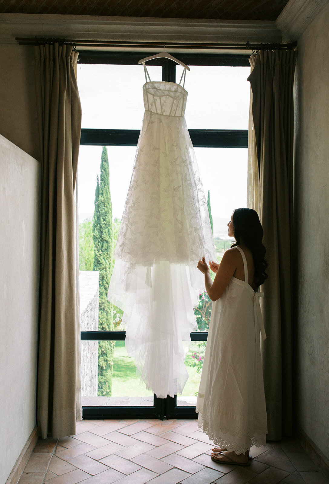 bride looks at her wedding dress hanging
