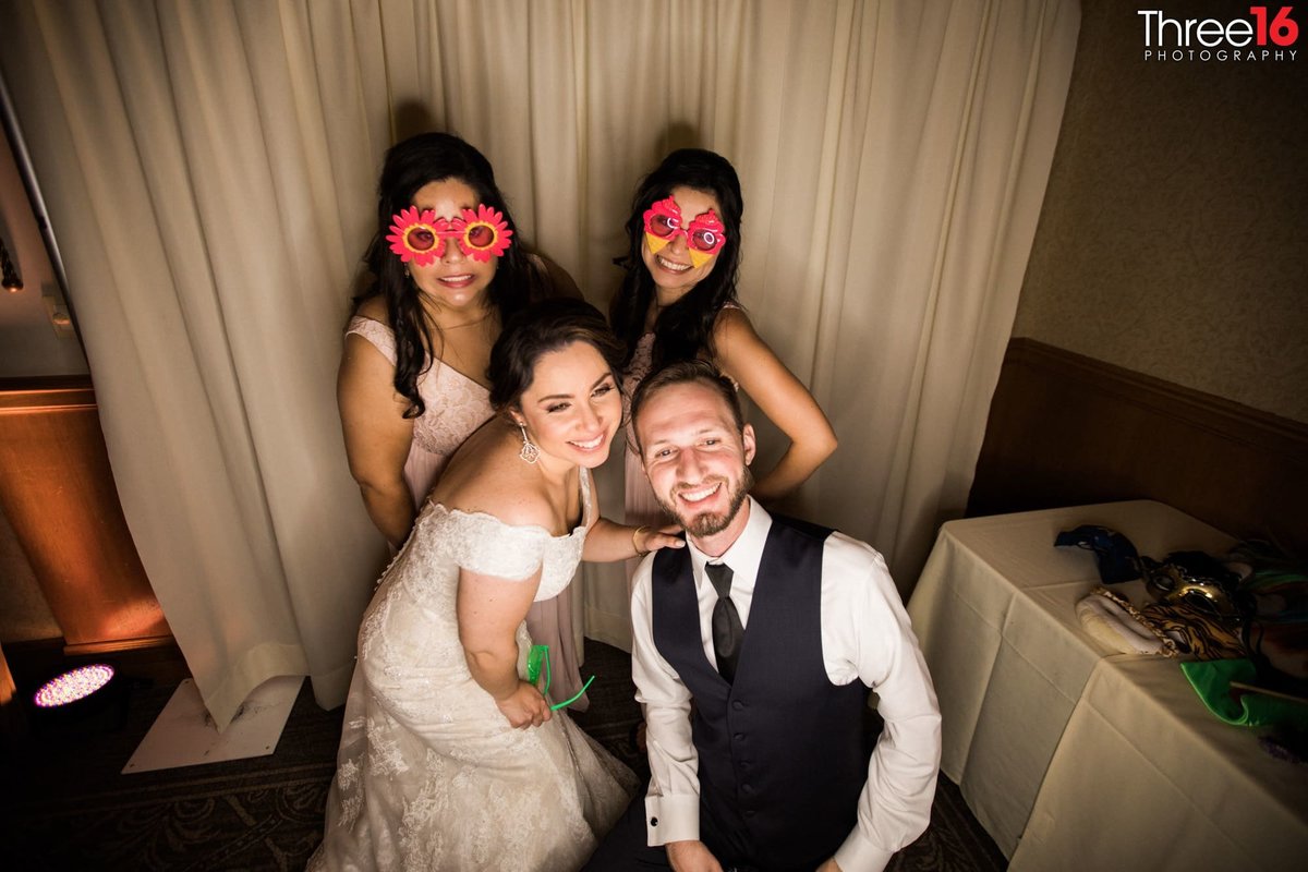 Bride and Groom pose with Bridesmaids wearing funny glasses