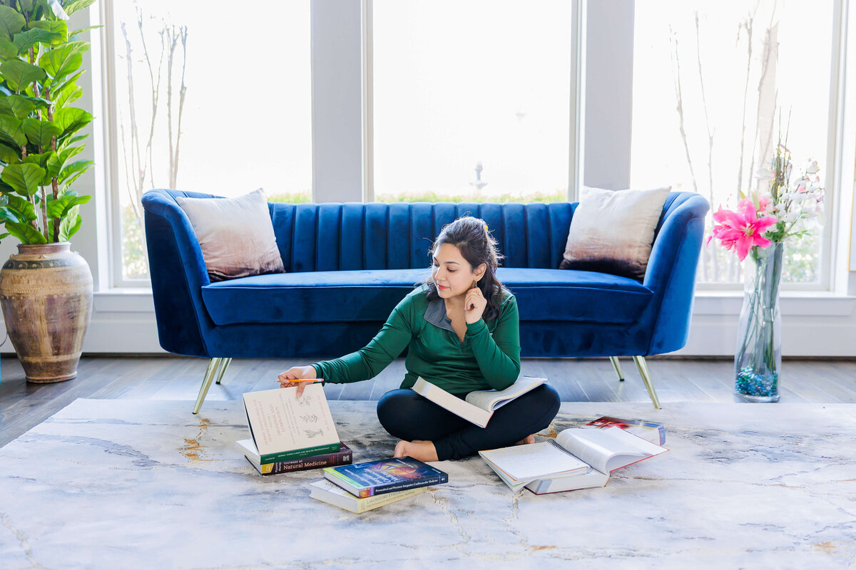Lady sitting on floor with books and wearing green top