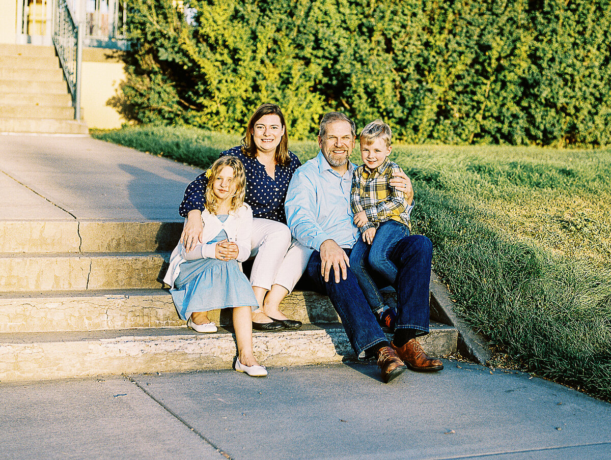 family of four sits on steps for photo at city park in denver