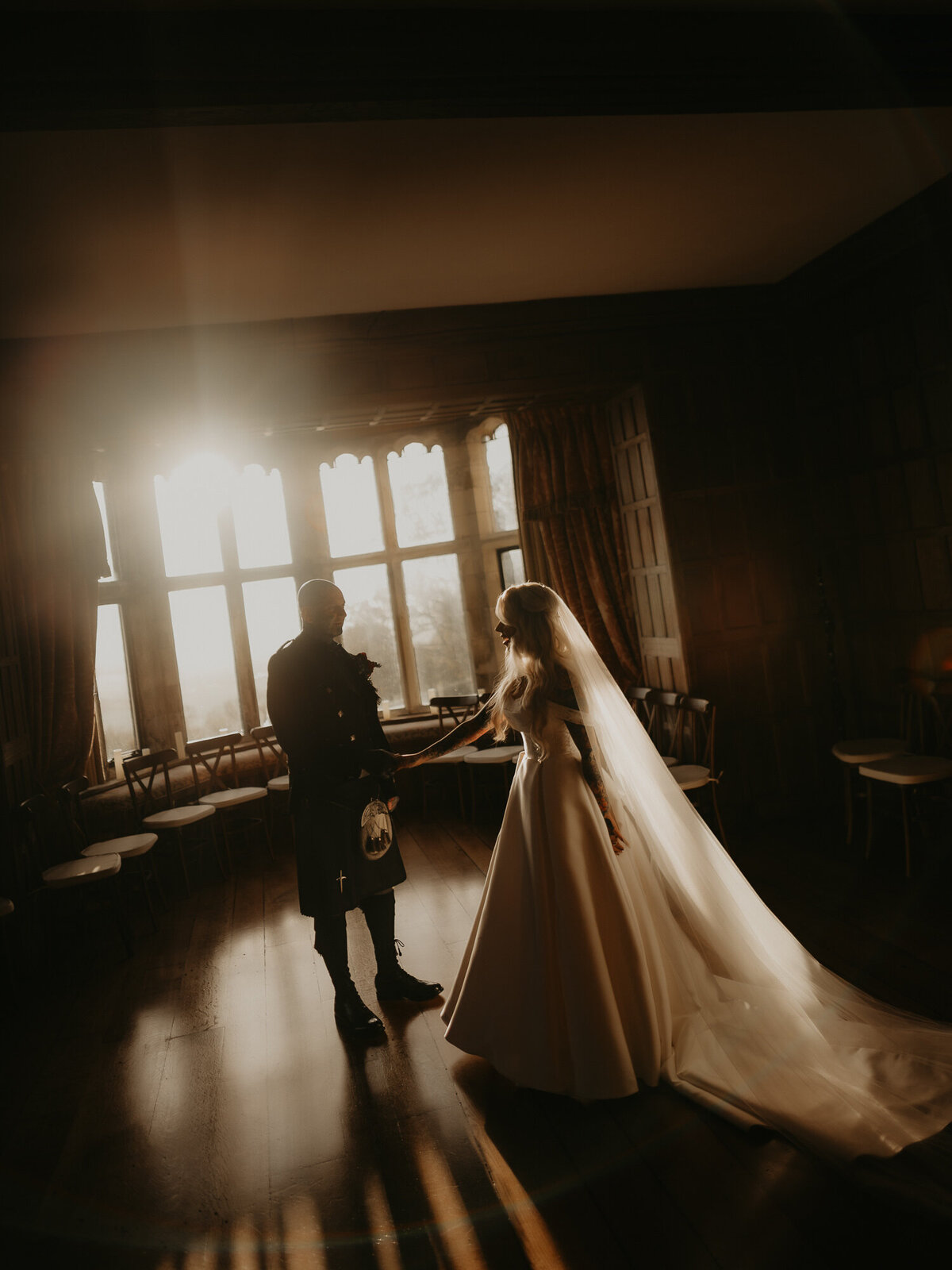 Sunset shines through a window at Lympne Castle in Kent as a tattooed bride and groom dance in the ceremony room. 