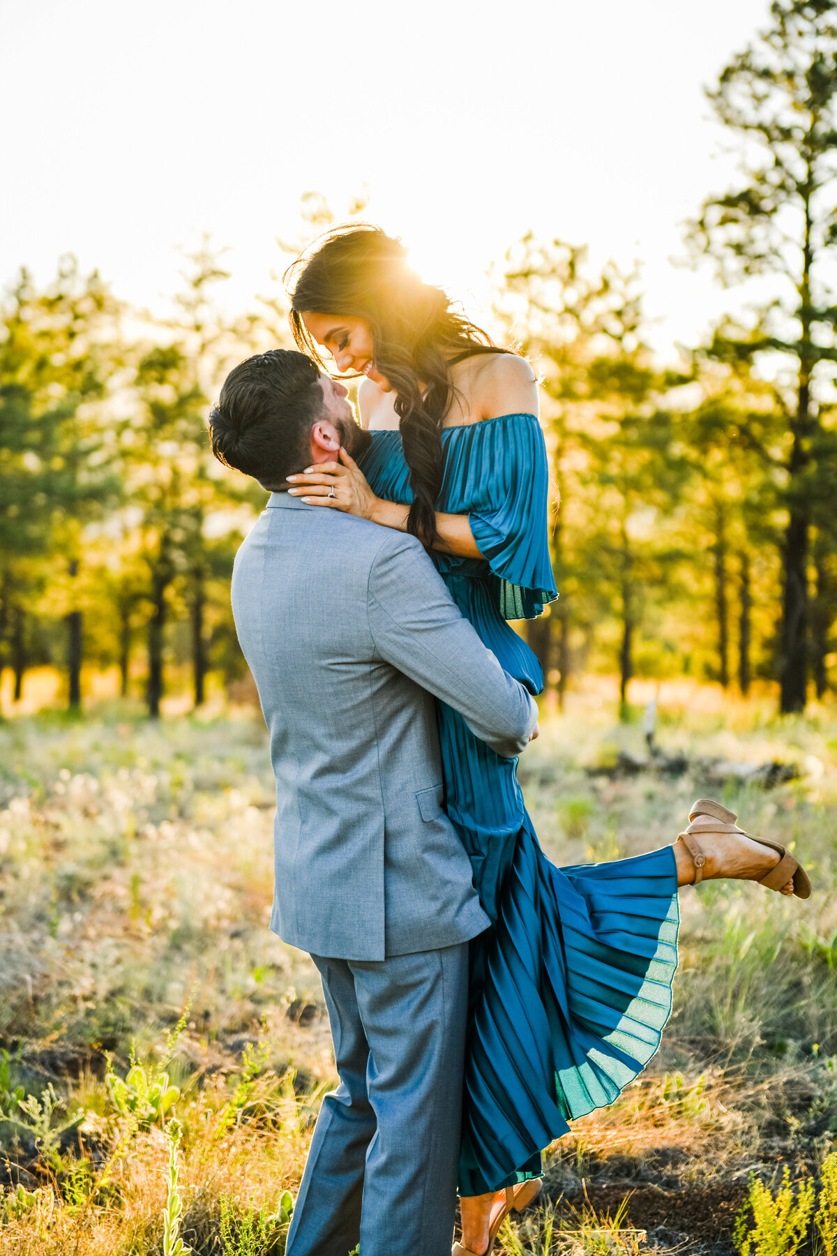 Engaged couple picking her up golden hour sunlight pine trees Flagstaff engagement photography