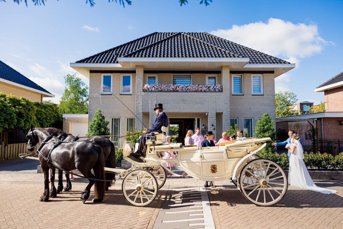 Bruidspaar vertrekt vanuit hun huis in een koets op weg naar de trouwlocatie, perfect georganiseerd door weddingplanner