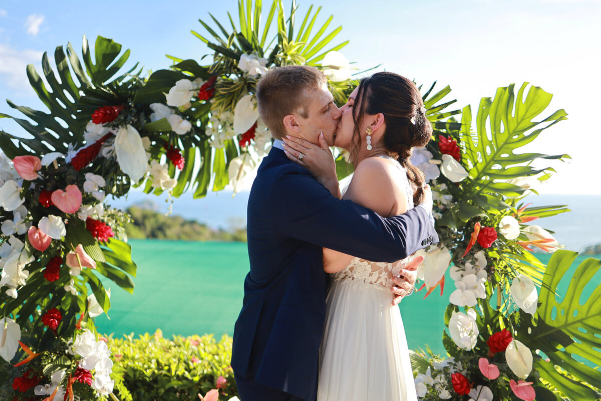 couple kissing in front of botanical alter