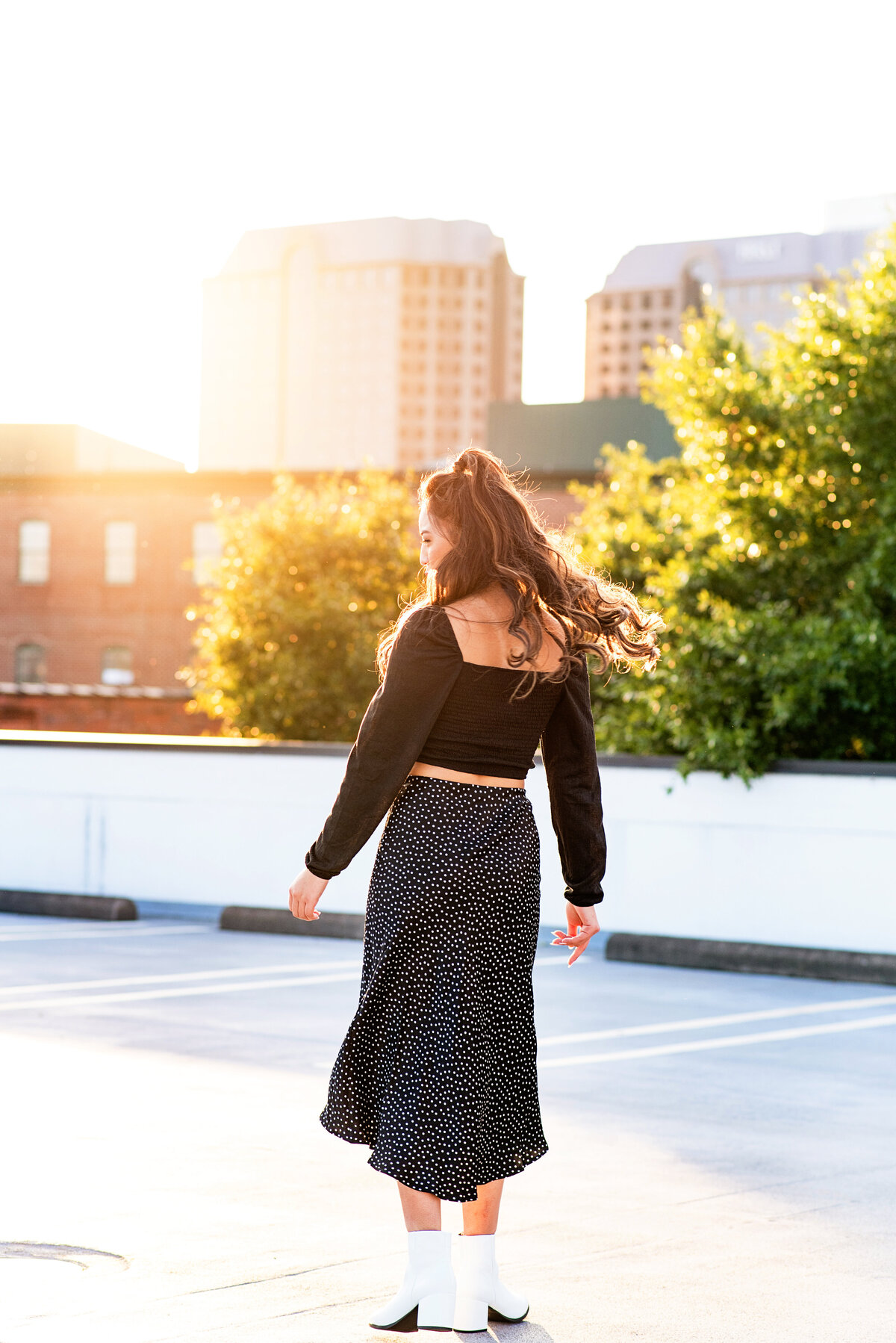 Rva senior girl twirls on rooftop at sunset during her senior pictures.