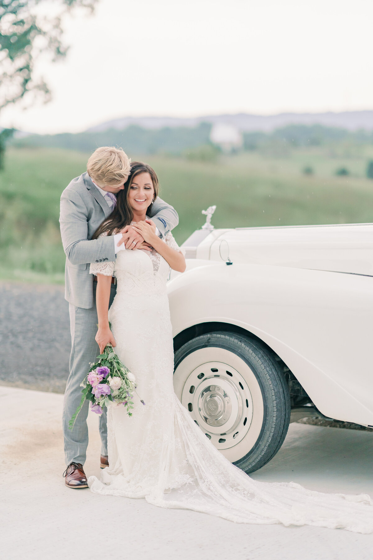 Couple embrace on their wedding day next to rolls royce