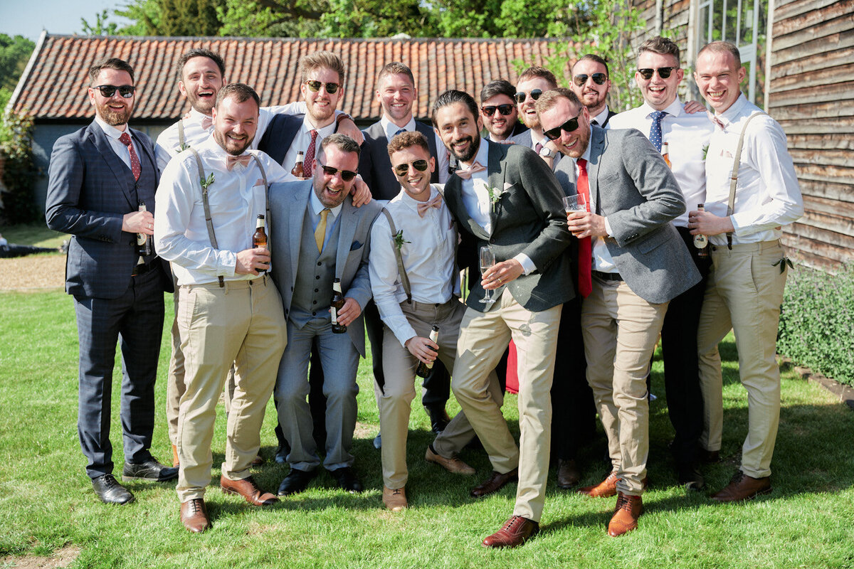 groom and his friends natural and relaxed group photo looking at camera at the barn wedding in henham park