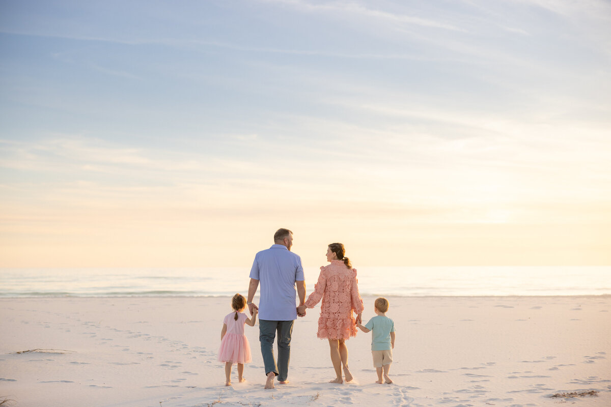 A family with two small kids walking at the beach at sunset