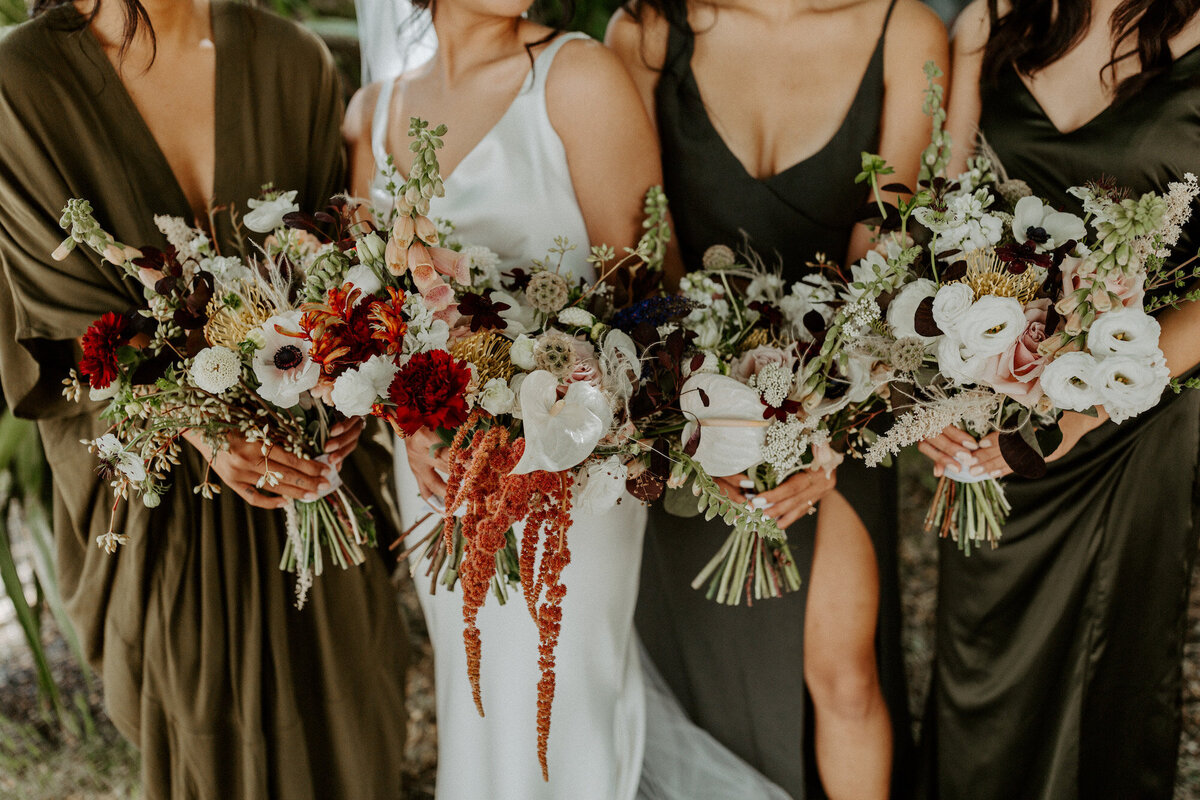 Bridesmaids wearing emerald velvet dresses and holding bouquets