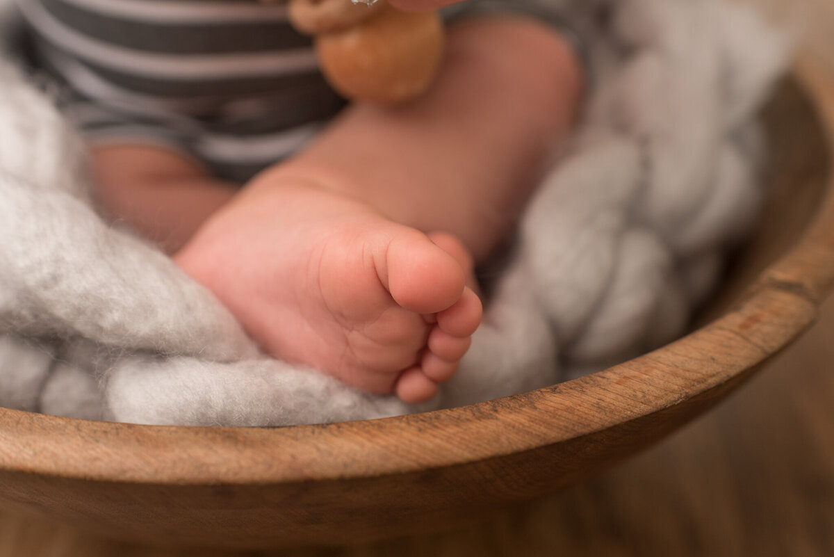 Close up picture of baby toes sitting in a wooden bowl