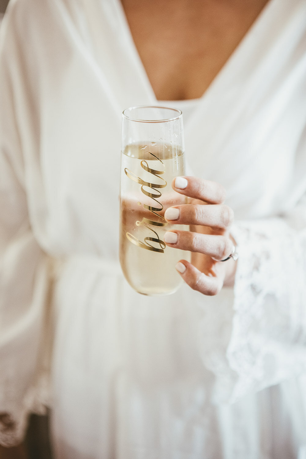 Woman holding glass of champagne with Bride calligraphy on glass