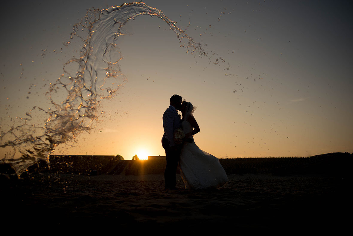 wave of water and bride and groom with sunset