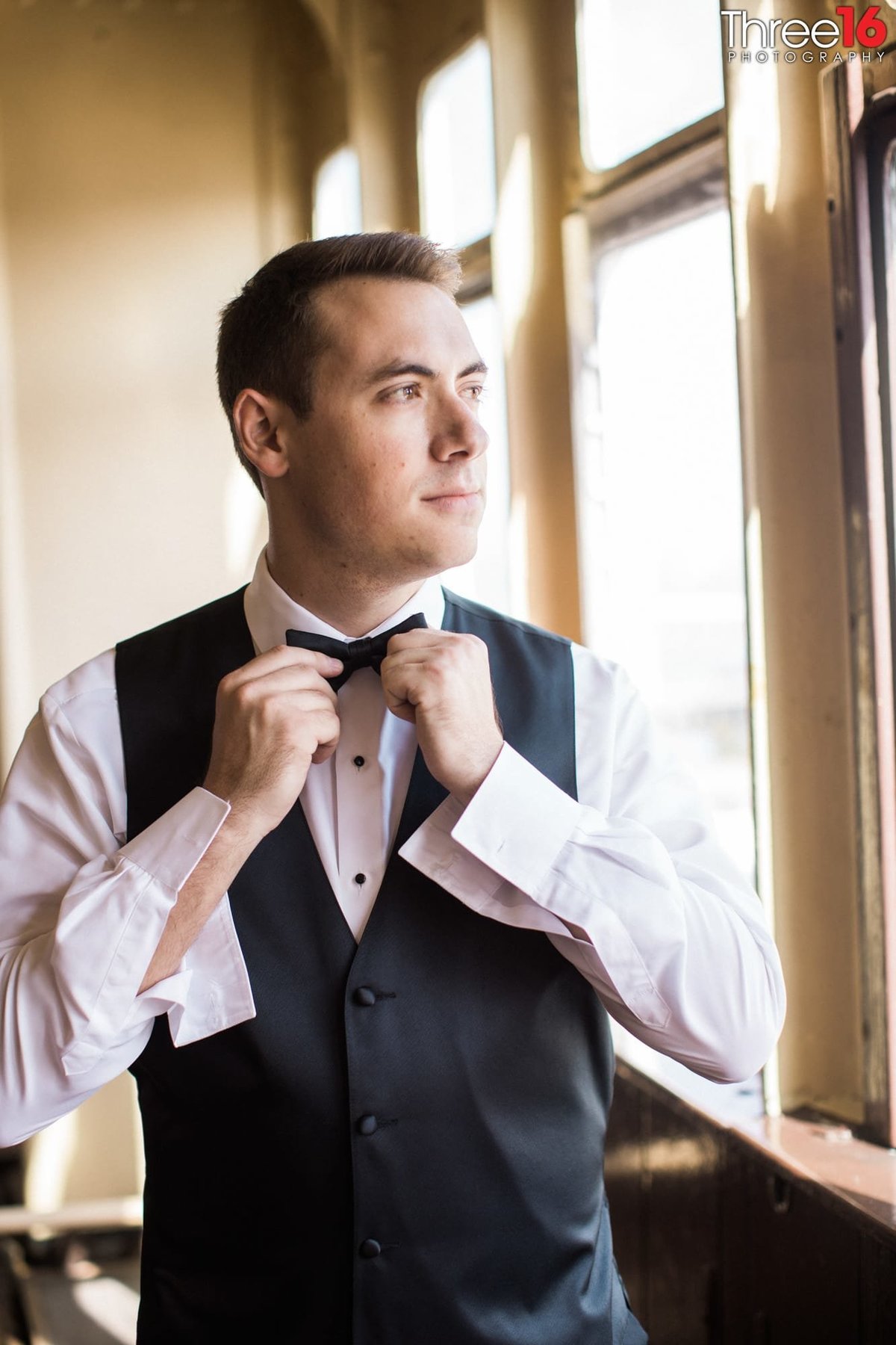 Groom straightening his bow tie before the ceremony