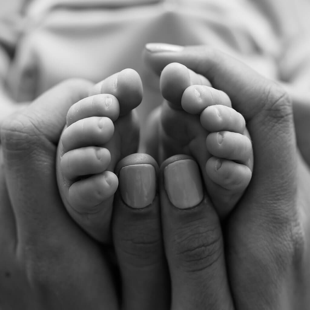 Black and white photo of  mommy holding newborns toes.