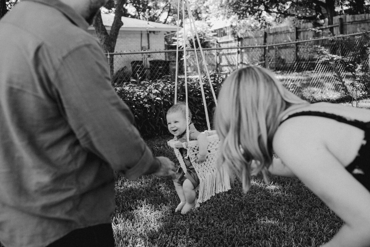 Child in swing with mother and father looking on