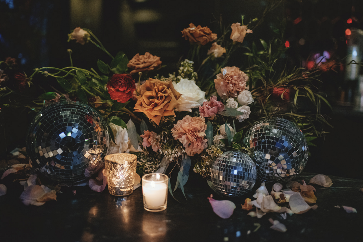 Dimly lit tea lights, small disco balls and multi-colored roses sit together to create on-trend centerpieces at Fort Lauderdale  wedding reception.