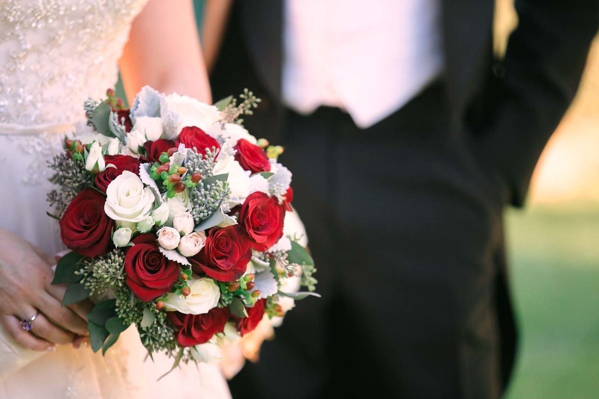 Bride holding a white and red rose bouquet at The Mansion at Oyster Bay