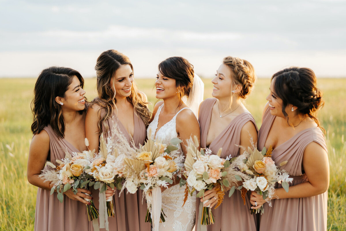 Bride and bridesmaids in dusty rose dresses with orange and white flowers